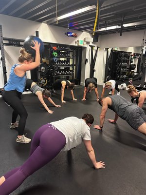 Training Studio - Group Classes - Our back-room training studio features four barbell racks, 2 cable stacks, amazing sound, and ALL the equipment needed to coach you through our programmed classes! We offer two group classes:
- Strong & Lean, which is a circuit-based strength and conditioning workout that will push you, but keep you coming back for more. This class is programmed around the fundamental lifts with barbells, kettlebells and dumbbells, mixed with functional movements to improve your athletic skills. Add in some great cardio equipment, and you have a HIIT weight and cardio training class.
- Fit AF, a high intensity complement to our Strong and Lean class. This one is a near-max effort interval workout. The intervals will be focused around our cardio machines: C2 Rower, C2 Ski-Erg, and Rogue Echo fan bike. We'll add bodyweight and light strength moves to balance out the workout.
We recommend this class be added to your routine 1-2 times per week to your strength training routine in our Strong & Lean, Power Reformer, Power Reformer Lite, or TRIBE Barbell classes. This class is designed for all levels of fitness from beginner to advanced. Training Studio - Group Classes - Our back-room training studio features four barbell racks, 2 cable stacks, amazing sound, and ALL the equipment needed to coach you through our programmed classes! We offer two group classes:
- Strong & Lean, which is a circuit-based strength and conditioning workout that will push you, but keep you coming back for more. This class is programmed around the fundamental lifts with barbells, kettlebells and dumbbells, mixed with functional movements to improve your athletic skills. Add in some great cardio equipment, and you have a HIIT weight and cardio training class.
- Fit AF, a high intensity complement to our Strong and Lean class. This one is a near-max effort interval workout. The intervals will be focused around our cardio machines: C2 Rower, C2 Ski-Erg, and Rogue Echo fan bike. We'll add bodyweight and light strength moves to balance out the workout.
We recommend this class be added to your routine 1-2 times per week to your strength training routine in our Strong & Lean, Power Reformer, Power Reformer Lite, or TRIBE Barbell classes. This class is designed for all levels of fitness from beginner to advanced.
