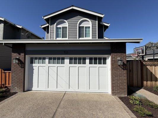 C.H.I carriage house Garage Door - Beautiful white carriage-house style garage door installation featuring decorative top-row windows and classic raised panel detailing. The new door complements the home’s dark exterior and brick accents, creating a clean, timeless look while enhancing curb appeal. C.H.I carriage house Garage Door - Beautiful white carriage-house style garage door installation featuring decorative top-row windows and classic raised panel detailing. The new door complements the home’s dark exterior and brick accents, creating a clean, timeless look while enhancing curb appeal.