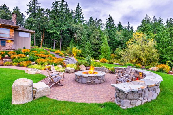 Gorgeous in the Gorge - Nestled on the Washington side of the Columbia River Gorge, this gorgeous estate boasts panoramic, breathtaking views of the Columbia River and its mountain sides. However, the client’s landscaping was high maintenance and outdated with huge lawns, uninviting retaining walls, an in-ground pool and a white picket fenced garden. They wanted a simplified landscape they could enjoy in their golden years without all the upkeep.
It was our job to not distract from the natural beauty and surroundings, and instead design something that added to the experience. Since the home was surrounded by forest, we suggested a simple design giving the appearance of the forest continuing up to the home. Many native plants were used in combination with non-native plants that have a native look, but would be more disease resistant, hardier & lower maintenance.
Additionally, boulders were incorporated throughout the landscape to make it look as natural as possible – lots and lots of boulders (about 150 tons). Fortunately, the client owned a quarry and delivered truckload after truckload of big, beautiful boulders.
The existing swimming pool was demolished, the pool house removed, hundreds of square feet of concrete retaining wall were replaced with boulder outcroppings, and an existing pergola and garden fencing went away. Much of the original lawn was replaced with a combination of boulders, walkways, dry river beds with dry waterfalls and a native-looking planting theme. Over 160 zoned, low-voltage lighting fixtures were installed that can be dimmed or turned off all from the convenience of their phone. A world-class fire pit was installed in a location that maximizes the panoramic views of the Gorge. Gorgeous in the Gorge - Nestled on the Washington side of the Columbia River Gorge, this gorgeous estate boasts panoramic, breathtaking views of the Columbia River and its mountain sides. However, the client’s landscaping was high maintenance and outdated with huge lawns, uninviting retaining walls, an in-ground pool and a white picket fenced garden. They wanted a simplified landscape they could enjoy in their golden years without all the upkeep.
It was our job to not distract from the natural beauty and surroundings, and instead design something that added to the experience. Since the home was surrounded by forest, we suggested a simple design giving the appearance of the forest continuing up to the home. Many native plants were used in combination with non-native plants that have a native look, but would be more disease resistant, hardier & lower maintenance.
Additionally, boulders were incorporated throughout the landscape to make it look as natural as possible – lots and lots of boulders (about 150 tons). Fortunately, the client owned a quarry and delivered truckload after truckload of big, beautiful boulders.
The existing swimming pool was demolished, the pool house removed, hundreds of square feet of concrete retaining wall were replaced with boulder outcroppings, and an existing pergola and garden fencing went away. Much of the original lawn was replaced with a combination of boulders, walkways, dry river beds with dry waterfalls and a native-looking planting theme. Over 160 zoned, low-voltage lighting fixtures were installed that can be dimmed or turned off all from the convenience of their phone. A world-class fire pit was installed in a location that maximizes the panoramic views of the Gorge.