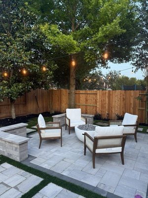 Elegant Outdoor Retreat- La Jolla - This backyard in La Jolla went from empty space to a true outdoor retreat. The goal was simple: create a modern, comfortable place where family and friends could gather year-round.
We designed a clean paver layout with natural grass inlays to keep it fresh and inviting. At the center, we added a round fire pit surrounded by custom seating that’s both stylish and comfortable. To finish it off, we strung warm café lights through the trees, giving the space that cozy, welcoming glow as the sun sets.
Now, our clients have the perfect spot for everything: from quiet mornings with coffee to evenings entertaining under the lights.
If you’re dreaming of your own backyard upgrade, our team would love to help bring it to life. Elegant Outdoor Retreat- La Jolla - This backyard in La Jolla went from empty space to a true outdoor retreat. The goal was simple: create a modern, comfortable place where family and friends could gather year-round.
We designed a clean paver layout with natural grass inlays to keep it fresh and inviting. At the center, we added a round fire pit surrounded by custom seating that’s both stylish and comfortable. To finish it off, we strung warm café lights through the trees, giving the space that cozy, welcoming glow as the sun sets.
Now, our clients have the perfect spot for everything: from quiet mornings with coffee to evenings entertaining under the lights.
If you’re dreaming of your own backyard upgrade, our team would love to help bring it to life.
