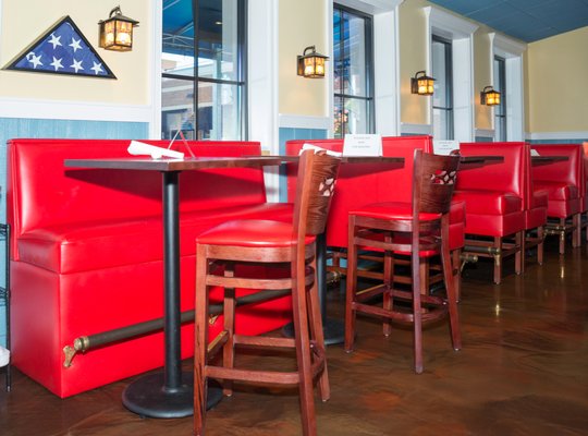 The Bungalow Alehouse - The Bungalow Alehouse is a local, family-owned smart casual bar and restaurant featuring over 80 brands of beer. This is a family friendly place where parents can bring their children and many singles also frequent the bar or come to play pool and meet.
The Alehouse was furnished in its entirety with our wood seating. All items, from wood chairs, bar stools, tables, and including the restaurant booths are made in the USA and fully customized. The premium Leonardo chairs in mahogany finish come with red vinyl padded seats that help to accentuate the wood. Matching premium Leonardo bar stools, help to create a coherent look. The fashionable chairs and bar stools add class without being too ostentatious.
Plain back bar booths, also in matching red vinyl were added. The bar height booths give customers a little oasis of privacy where they can socialize with friends and family with a little fun added to the mix by the height of the booths. Like all of the other furniture we make, the booths are fully customizable. Solid wood table tops in dark mahogany finish with eased edge go well with the seating. The Bungalow Alehouse - The Bungalow Alehouse is a local, family-owned smart casual bar and restaurant featuring over 80 brands of beer. This is a family friendly place where parents can bring their children and many singles also frequent the bar or come to play pool and meet.
The Alehouse was furnished in its entirety with our wood seating. All items, from wood chairs, bar stools, tables, and including the restaurant booths are made in the USA and fully customized. The premium Leonardo chairs in mahogany finish come with red vinyl padded seats that help to accentuate the wood. Matching premium Leonardo bar stools, help to create a coherent look. The fashionable chairs and bar stools add class without being too ostentatious.
Plain back bar booths, also in matching red vinyl were added. The bar height booths give customers a little oasis of privacy where they can socialize with friends and family with a little fun added to the mix by the height of the booths. Like all of the other furniture we make, the booths are fully customizable. Solid wood table tops in dark mahogany finish with eased edge go well with the seating.