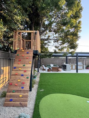 Practical Beauty Backyard - Who wouldn’t want a backyard like this? Beautiful + Functional! 
Kids’ Play Area – A treehouse with a climbing wall and soft artificial turf for safe, endless fun.
 Outdoor Kitchen – A durable, weather-resistant BBQ & bar area with seamless Pour-in-Place Concrete, perfect for gatherings.
Refined Details – Herringbone pavers, LED-lit stepping concrete, and a wide pergola for shade and ambiance.
A perfect blend of style and comfort, making this backyard truly exceptional!