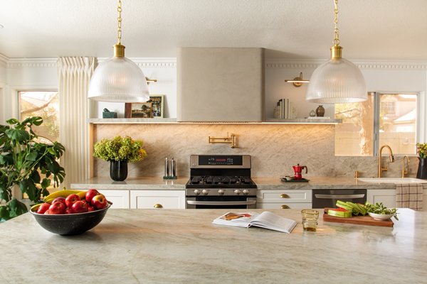 Peccole Ranch Kitchen - This kitchen underwent a dramatic transformation from a dated tract-home layout into a sleek, modern space. We designed a clean, contemporary look featuring a custom Roman clay hood as the centerpiece, complemented by quartz countertops with dual waterfall edges and a matching quartz backsplash. The striking green island adds a pop of color and character, while an undermount sink and built-in drawer microwave provide convenience. LED lights under the stone shelves and under the cabinets highlight the details beautifully, and abundant cabinetry ensures plenty of storage without sacrificing style. Peccole Ranch Kitchen - This kitchen underwent a dramatic transformation from a dated tract-home layout into a sleek, modern space. We designed a clean, contemporary look featuring a custom Roman clay hood as the centerpiece, complemented by quartz countertops with dual waterfall edges and a matching quartz backsplash. The striking green island adds a pop of color and character, while an undermount sink and built-in drawer microwave provide convenience. LED lights under the stone shelves and under the cabinets highlight the details beautifully, and abundant cabinetry ensures plenty of storage without sacrificing style.