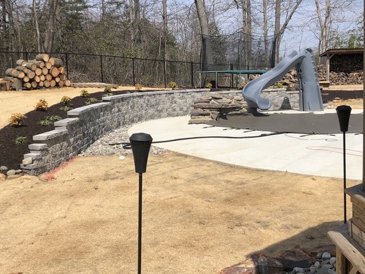 Retaining wall installation - This wall is curved and tiered to accommodate the layout of the property, and retain hill to promote proper water run off around and away from pool. Glad customer chose to add lighting which was the perfect finishing touch. We also did the finish grading.