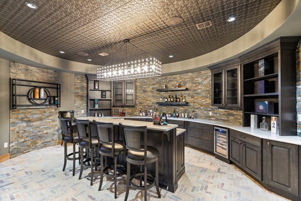 Basement in Mclean 2024 - This is where the old world meets the eclectic modern era. This couple recently purchased their
mansion in one of the most prominent gated-community in McLean, VA.
With lots in their plate, they wanted to transform their basement into an upscale entertainment area
for their frequent friends and family gathering. Husband desired a large-scale bar and gaming room,
while wife wanted her secluded wine cellar and tasting area.
After consulting our design staff, it was time to bring the drafted sketches into reality. By the way of
moving few loads bearing interior walls and install steel beams to support second for stone fireplace, we
made headway to achieve gaining a big floor area, and it was just perfect to lay-out our massive bar in
middle of it. Excavating through concrete slab for plumbing and drain lines were laid for bar sink, ice
maker and much more.
The herringbone solid brick floor has enhanced the early Florance back street look under starry hanging
Italian string lights. The dark and rustic cherry cabinetry with exotic stone top surrounded with
ledgestone on its walls wrapped all around this bar room.
Copper ceiling panels was magnificent touch to bring in eclectic look, hammered copper sink and
beautiful chandelier were just few of our designer touches to upscale this bodega.
Just to left of this bar we have opened a bearing wall and lay-out our wine cellar room through a knotty
pine door. Wrapped in irregular veneer stone walls, customer wine racks with tasting island in dark
Mahogony wine racks brought her dream to reality. We have installed a new chilling system foe climate
control for her prized wine selections. Gathering, drinking wine and gossiping just met their match.
One of his bucket lists was the poker/gaming room just outside from the crowded area. We have set a
secluded space few steps down from main area, featured with a 70-gallon aquarium on the back wall
and a very unique hanging lights over the poker table.
Archways, knotty pine doors and large-scale old look porcelain tiles are just to name a few other for this
unique and very old-world Italian pub. Basement in Mclean 2024 - This is where the old world meets the eclectic modern era. This couple recently purchased their
mansion in one of the most prominent gated-community in McLean, VA.
With lots in their plate, they wanted to transform their basement into an upscale entertainment area
for their frequent friends and family gathering. Husband desired a large-scale bar and gaming room,
while wife wanted her secluded wine cellar and tasting area.
After consulting our design staff, it was time to bring the drafted sketches into reality. By the way of
moving few loads bearing interior walls and install steel beams to support second for stone fireplace, we
made headway to achieve gaining a big floor area, and it was just perfect to lay-out our massive bar in
middle of it. Excavating through concrete slab for plumbing and drain lines were laid for bar sink, ice
maker and much more.
The herringbone solid brick floor has enhanced the early Florance back street look under starry hanging
Italian string lights. The dark and rustic cherry cabinetry with exotic stone top surrounded with
ledgestone on its walls wrapped all around this bar room.
Copper ceiling panels was magnificent touch to bring in eclectic look, hammered copper sink and
beautiful chandelier were just few of our designer touches to upscale this bodega.
Just to left of this bar we have opened a bearing wall and lay-out our wine cellar room through a knotty
pine door. Wrapped in irregular veneer stone walls, customer wine racks with tasting island in dark
Mahogony wine racks brought her dream to reality. We have installed a new chilling system foe climate
control for her prized wine selections. Gathering, drinking wine and gossiping just met their match.
One of his bucket lists was the poker/gaming room just outside from the crowded area. We have set a
secluded space few steps down from main area, featured with a 70-gallon aquarium on the back wall
and a very unique hanging lights over the poker table.
Archways, knotty pine doors and large-scale old look porcelain tiles are just to name a few other for this
unique and very old-world Italian pub.