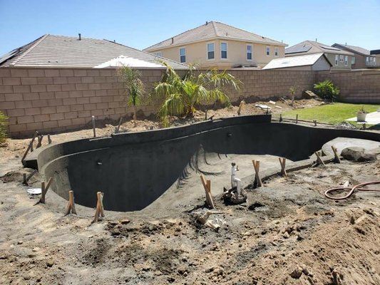 lancaster pool project - this is a brand new swimming pool with a fresh modern baja and two water features artificial rock with mid broom finish light grey concrete decking