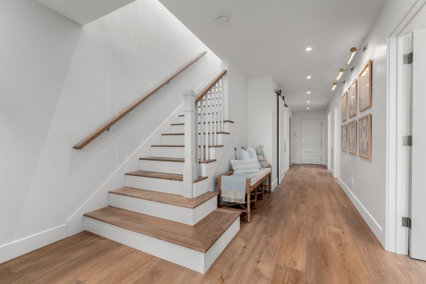 Shell House - Completed in 2017, this existing Newport Beach home is a 3-story single-family detached condo within a 44-unit complex built by Taylor Morrison Homes.  

The homeowners loved the location of the unit, just steps from the beach, but it didn’t quite fit their family’s needs. However, the planned unit development is highly restricted by jurisdictional conditions, limiting the floor area and exterior modifications. Extensive research through hundreds of pages for Homeowner Association Guidelines, CC&Rs, and building and zoning code was required to identify a path to achieve the client’s goals. 

Every floor was redesigned in some capacity to incorporate additional bedrooms and bathrooms. At the entry, the stair approach was modified to make it more welcoming and increase the hallway width. The parlor on the first floor was converted to a bedroom. A simple adjustment of compartmentalizing the laundry room from the garage access door allowed the adjacent bathroom door to move to the main hallway, which allowed the size of the bathroom and bedroom closet to increase. 

On the second floor, a full bathroom that was accessible off the kitchen was converted to a powder bath. The shower was used for a new on-suite bathroom to replace a modest walk-in closet in an existing bedroom. An underutilized niche was converted into a linear closet. 

The entire third floor was previously dedicated to the primary suite. However, the homeowner had to leave their bedroom to walk through an open hallway to get to their primary bathroom and closet. The roof deck access stairs were relocated to make room for a new primary bathroom, creating a true primary suite. An additional laundry space, bathroom and bedroom were added to the third floor in place of the previous primary bathroom and closet. 

The roof deck size was increased, and a fireplace was added to make a more useable space to enjoy the amazing view and entertain guests into the evening.