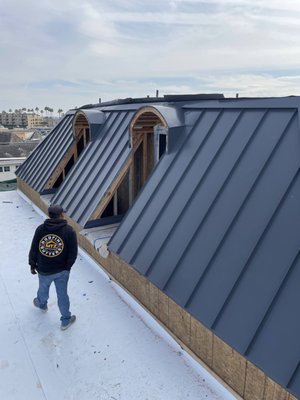 EDGEWATER HB - Sleek and Modern Standing Seam Metal Roof at Edgewater HB. Featuring durable Galvalume Metal with a Black Kynar Finish, this roof exemplifies contemporary design. The custom-fabricated chimney cap complements the structure beautifully.
