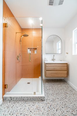 Modern Spanish-Style Shower Remodel - This shower remodel combines earthy elegance with a touch of luxury. The walls are adorned with beautiful terra cotta tiles, adding warmth to the space. The showers' centerpiece is the satin brass faucet trim, which complements the tiles perfectly. A floating vanity with matching satin brass faucets completes the look, creating a stylish bathroom retreat that blends natural elements. Modern Spanish-Style Shower Remodel - This shower remodel combines earthy elegance with a touch of luxury. The walls are adorned with beautiful terra cotta tiles, adding warmth to the space. The showers' centerpiece is the satin brass faucet trim, which complements the tiles perfectly. A floating vanity with matching satin brass faucets completes the look, creating a stylish bathroom retreat that blends natural elements.