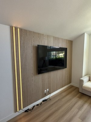 Custom Wood Slat Accent Wall with LED Lighting in Riverside, CA - We recently completed this custom wood slat accent wall installation for a living room in Riverside, CA, turning a plain television wall into a warm, modern center of attention.
The project began with measurements and layout planning so that every wood slat wall panel would be evenly aligned throughout the space. We laser leveled the whole installation to keep the vertical lines straight and to make sure the spacing was consistent from one side of the wall to the other.
Each decorative wall panel was custom measured, cut and fitted around all existing electrical outlets, TV connections, baseboards, ceiling and adjoining walls. Great care was taken with the edges and transitions so that there were no uneven gaps or unfinished areas.
We also added custom vertical LED lighting to the accent wall to provide some warm ambient light and a more modern architectural look to the finished TV wall. The old TV mount blended nicely with the new wall paneling, and the TV was put back up once the accent wall was complete.
The finished feature wall is in natural wood tones, with sharp vertical lines and custom LED lighting and is installed perfectly, to totally change the look of the living room without a full remodel.
Another custom home remodel project is complete in Riverside, California and most importantly a very happy client with the end result. Custom Wood Slat Accent Wall with LED Lighting in Riverside, CA - We recently completed this custom wood slat accent wall installation for a living room in Riverside, CA, turning a plain television wall into a warm, modern center of attention.
The project began with measurements and layout planning so that every wood slat wall panel would be evenly aligned throughout the space. We laser leveled the whole installation to keep the vertical lines straight and to make sure the spacing was consistent from one side of the wall to the other.
Each decorative wall panel was custom measured, cut and fitted around all existing electrical outlets, TV connections, baseboards, ceiling and adjoining walls. Great care was taken with the edges and transitions so that there were no uneven gaps or unfinished areas.
We also added custom vertical LED lighting to the accent wall to provide some warm ambient light and a more modern architectural look to the finished TV wall. The old TV mount blended nicely with the new wall paneling, and the TV was put back up once the accent wall was complete.
The finished feature wall is in natural wood tones, with sharp vertical lines and custom LED lighting and is installed perfectly, to totally change the look of the living room without a full remodel.
Another custom home remodel project is complete in Riverside, California and most importantly a very happy client with the end result.