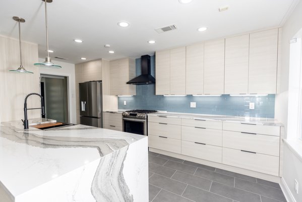 Contemporary Kitchen Remodel - Total Kitchen Transformation

In this complete kitchen overhaul, we rejuvenated the space from floor to ceiling, crafting a modern yet welcoming atmosphere that balances functionality with aesthetic elegance.

Flooring and Ceiling
We began by installing new tile flooring, providing a durable and stylish foundation. The ceiling was refreshed to create a seamless and cohesive look, enhancing the overall feel of the kitchen.

Painting and Cabinetry
Freshly painted walls now blend perfectly with the new design elements. The European-style pale pine cabinetry adds a touch of modern sophistication while brightening the space. A new peninsula, featuring a waterfall-edge countertop, serves as a bold focal point, marrying elegance with practicality.

Countertops and Backsplash
We installed Apollo quartz countertops, a sleek and durable surface perfect for everyday kitchen use. The backsplash was thoughtfully selected to complement the countertops, creating visual harmony while making cleaning and maintenance easier.

Lighting Enhancements
Lighting upgrades were both functional and decorative. Under-cabinet lighting enhances task visibility and highlights the cabinetry’s craftsmanship. Elegant pendant lights above the peninsula create a stylish focal point, while energy-efficient LED recessed lights ensure the entire kitchen is bright and inviting for daily use.

Plumbing & Electrical
We upgraded the plumbing system and installed a new sink, ensuring lasting performance and reliability. Electrical systems were also enhanced to support the modern lighting and appliances, providing safety and energy efficiency throughout the space.

This kitchen transformation is a perfect blend of contemporary design and practical upgrades. High-quality materials and expert craftsmanship have turned this kitchen into a beautiful, functional centerpiece of the home.
