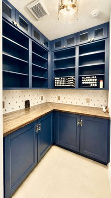 Kitchen Pantry Remodel - This Collin County remodel features a custom pantry with blue shaker birch cabinetry, soft-close doors and rollouts, custom open shelving, butcher block countertop, and a new tile backsplash. Built with hardwood and plywood for lasting durability, the finished pantry delivers both functional storage and a custom, high-end look for this project located in The Colony, Texas.
