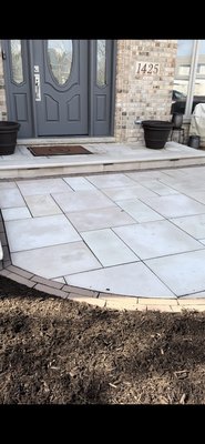 Custom Front Entrance Paver Patio with Seating Area & Decorative Flower Stands - Beautifully designed front entrance paver patio featuring a welcoming entertainment space and custom-built flower stand pillars. This project included full excavation, compacted base installation, and precision placement of large-format pavers for a clean, modern appearance. Decorative border accents and natural stone caps were added to enhance the overall design, while the built-in seating wall and flower stands create the perfect space for relaxing and elevating the home’s curb appeal. This installation combines functionality, durability, and elegance to create a stunning front entrance.