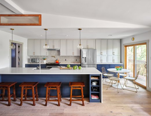 Warm Modern Grey and Blue Kitchen Cabinet Painting Project in Rollingwood, TX - This gorgeous two-toned kitchen in Rollingwood, TX is one of our favorite transformations!  Before we painted them, these cabinets were a grainy wood that not only made the space feel closed off, since all you saw was a wall of heavy cabinets. Our expert cabinet refinishers painted the upper cabinets in Benjamin Moore "Stonington Grey", and lowers in "Hale Navy".  Now the kitchen does the entire, open-plan space justice! It's a perfect example of how choosing the right paint colors can make your kitchen feel a decade newer and more open and chic.  Browse through our gallery of kitchen before-and-after transformations on our website for more inspiration.  The first step towards loving your home again is easy - just schedule a free in-home painting estimate, and see what we can do for you!