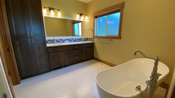 Bathroom Remodel - Customer had this home built a couple years ago but was never happy with how the bathroom turned out. Tile was improperly installed and access to the tub was difficult due to a large tile surround. We pulled everything out, installed new underlayment, 2"x2" matte hexagon tiles, a gorgeous freestanding tub and faucet, bright tile backsplash and made a custom mirror frame to finish it off. Bathroom Remodel - Customer had this home built a couple years ago but was never happy with how the bathroom turned out. Tile was improperly installed and access to the tub was difficult due to a large tile surround. We pulled everything out, installed new underlayment, 2"x2" matte hexagon tiles, a gorgeous freestanding tub and faucet, bright tile backsplash and made a custom mirror frame to finish it off.