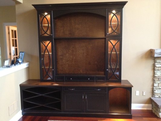 Custom Entertainment Center made of Maple wood featuring designer wood and glass doors, wine rack and lighting. Beautiful rubbed through fin - High end custom built in Cabinets and bars hand crafted and finished by Mckay’s Custom Cabinets. Com Custom Entertainment Center made of Maple wood featuring designer wood and glass doors, wine rack and lighting. Beautiful rubbed through fin - High end custom built in Cabinets and bars hand crafted and finished by Mckay’s Custom Cabinets. Com