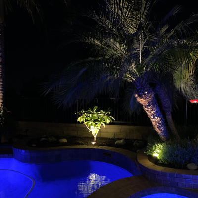 Landscape Lighting Well Lights - When it comes to landscape design, the power of uplighting can't be overstated. It's a simple yet incredibly impactful way to add visual interest to any space without risking being overwhelming. Not only that, but a good in-ground well light can deliver loads of value in terms of practicality. Read on as we explore this specific type of uplight, identify common places it's used outdoors, and go over some best practices and tips to keep in mind when incorporating them into your own yard.
What are In-Ground Well Lights?
In-Ground Well Lights are a type of outdoor lighting specifically designed for illuminating the an object or surface from below. They are installed below ground level, and aside from the light they emit, are not easily noticeable to the casual observer.
In-ground well lights have a variety of uses, including outdoor pathways, accent lighting for gardens or landscape features, and security lighting. While aesthetics aren't necessarily a priority with this type of lighting product, you'll definitely find them in several different shapes and sizes.
Frames themselves are often made from PVC, aluminum, solid brass, or stainless steel. They're colored to blend in with natural surroundings, whether that's green foliage or a stone patio. Some people also choose to install in-ground lights that contrast their environment, such as metal frames against a wood fence.
How In-Ground Well Lights Work
The most common style of in-ground well light is the low voltage type, which uses a transformer to reduce standard household voltage from 120 volts to 12 volts. A low voltage system is often the preferred choice of homeowners because of its cost-effectiveness and ease of installation.
As for the bulbs themselves, in-ground well lights can be either incandescent or LED. Incandescent bulbs are the most economical option but they also produce more heat, so they can be a bit of a fire hazard. LED bulbs on the other hand require less wattage to produce the same amount of light and last much longer than incandescent bulbs.
A few other parts and systems are involved in making an in-ground system work. The typical setup requires not only lights, but also an outdoor rated junction box, cable splices, conduit and wire. The junction box houses the transformer and other electrical components needed to power the well lights. It is usually installed near or in the ground in an area that is away from foot traffic yet still accessible for maintenance purposes when needed.
Those who wish to control their lights can also invest in a light control system. There are many kinds out there, from simple on/off switches to more advanced motion sensor or time-based controllers. These can allow you to set up automated lighting scenarios that turn the lights on and off at certain times of the day or when movement is detected near them. An extra step and cost, but certainly worthwhile if you're looking to upstage your yard.
Where In-Ground Well Lights are Used
So, where can you find in-ground well lights? Per the name, these lights can be installed in virtually any spot below ground level. They are easiest to set up in dirt or mulch gardens, but plenty of homeowners and landscapers opt to make in-ground well lights a characteristic element of their patios, walkways, and balconies too.
Let's take a closer look at some of the most common places in which these fixtures are used outdoors:
Trees
Trees are beautiful as-is; nothing can replicate Mother Nature's distinct beauty and eye for detail.
That being said, incorporating in-ground well lights to highlight certain features of a tree adds an extra touch of glamour and gives guests something special to take away with them. In particular, these lighting fixtures are excellent for illuminating the trunk of a tree, while also casting shadowed details on the branches.
Flowers and Plants
The pinpoint beams of light created by in-groud well fixtures add depth to flower beds and planters. These lights are great for highlighting the unique colors of a plant's foliage, as well as adding dimension to a garden.
Pathways & Walkways
In-ground well lights are ideal for creating an illuminated pathway or walkway. The subtle lighting is just enough to provide guests with the visibility they need yet not so much that it is overwhelming.
Water Features
Water features make excellent use of in-ground well lights. The fixtures can be placed around the perimeter or in specific areas to emphasize the beauty of a waterfall or pond.
Columns
Although many columns are already dramatic in nature, they and similar architectural features can look even better when up-lit.
Upgrading Your Yard With In-Ground Well Lights
Installing in-ground well lights alone is sure to take your property's aesthetic up a notch. But what about a couple more notches? These extra tips and best practices can make everyday installations look even better. Landscape Lighting Well Lights - When it comes to landscape design, the power of uplighting can't be overstated. It's a simple yet incredibly impactful way to add visual interest to any space without risking being overwhelming. Not only that, but a good in-ground well light can deliver loads of value in terms of practicality. Read on as we explore this specific type of uplight, identify common places it's used outdoors, and go over some best practices and tips to keep in mind when incorporating them into your own yard.
What are In-Ground Well Lights?
In-Ground Well Lights are a type of outdoor lighting specifically designed for illuminating the an object or surface from below. They are installed below ground level, and aside from the light they emit, are not easily noticeable to the casual observer.
In-ground well lights have a variety of uses, including outdoor pathways, accent lighting for gardens or landscape features, and security lighting. While aesthetics aren't necessarily a priority with this type of lighting product, you'll definitely find them in several different shapes and sizes.
Frames themselves are often made from PVC, aluminum, solid brass, or stainless steel. They're colored to blend in with natural surroundings, whether that's green foliage or a stone patio. Some people also choose to install in-ground lights that contrast their environment, such as metal frames against a wood fence.
How In-Ground Well Lights Work
The most common style of in-ground well light is the low voltage type, which uses a transformer to reduce standard household voltage from 120 volts to 12 volts. A low voltage system is often the preferred choice of homeowners because of its cost-effectiveness and ease of installation.
As for the bulbs themselves, in-ground well lights can be either incandescent or LED. Incandescent bulbs are the most economical option but they also produce more heat, so they can be a bit of a fire hazard. LED bulbs on the other hand require less wattage to produce the same amount of light and last much longer than incandescent bulbs.
A few other parts and systems are involved in making an in-ground system work. The typical setup requires not only lights, but also an outdoor rated junction box, cable splices, conduit and wire. The junction box houses the transformer and other electrical components needed to power the well lights. It is usually installed near or in the ground in an area that is away from foot traffic yet still accessible for maintenance purposes when needed.
Those who wish to control their lights can also invest in a light control system. There are many kinds out there, from simple on/off switches to more advanced motion sensor or time-based controllers. These can allow you to set up automated lighting scenarios that turn the lights on and off at certain times of the day or when movement is detected near them. An extra step and cost, but certainly worthwhile if you're looking to upstage your yard.
Where In-Ground Well Lights are Used
So, where can you find in-ground well lights? Per the name, these lights can be installed in virtually any spot below ground level. They are easiest to set up in dirt or mulch gardens, but plenty of homeowners and landscapers opt to make in-ground well lights a characteristic element of their patios, walkways, and balconies too.
Let's take a closer look at some of the most common places in which these fixtures are used outdoors:
Trees
Trees are beautiful as-is; nothing can replicate Mother Nature's distinct beauty and eye for detail.
That being said, incorporating in-ground well lights to highlight certain features of a tree adds an extra touch of glamour and gives guests something special to take away with them. In particular, these lighting fixtures are excellent for illuminating the trunk of a tree, while also casting shadowed details on the branches.
Flowers and Plants
The pinpoint beams of light created by in-groud well fixtures add depth to flower beds and planters. These lights are great for highlighting the unique colors of a plant's foliage, as well as adding dimension to a garden.
Pathways & Walkways
In-ground well lights are ideal for creating an illuminated pathway or walkway. The subtle lighting is just enough to provide guests with the visibility they need yet not so much that it is overwhelming.
Water Features
Water features make excellent use of in-ground well lights. The fixtures can be placed around the perimeter or in specific areas to emphasize the beauty of a waterfall or pond.
Columns
Although many columns are already dramatic in nature, they and similar architectural features can look even better when up-lit.
Upgrading Your Yard With In-Ground Well Lights
Installing in-ground well lights alone is sure to take your property's aesthetic up a notch. But what about a couple more notches? These extra tips and best practices can make everyday installations look even better.