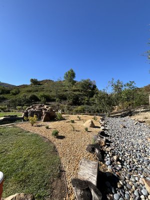 Gravel Installation w/ Planting - Dario Landscaping installed Mojave Desert Gold 3/4" Gravel with 12 drought-tolerant plants in the client's backyard. The project involved removing approximately 2 inches of impervious soil and regrading the entire location. The plants were selected based on what would do the best in each landscaping area. A landscaping fabric was installed prior to laying down the gravel to ensure minimal weed growth. Likewise, a walkway was created so the client could get to her pool pumps when necessary.