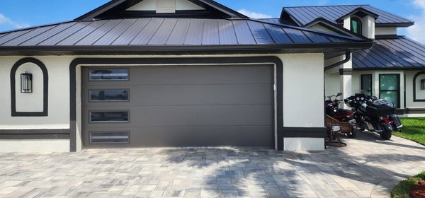 Homefront MAKEOVER! - Check out this sleek upgrade!  We installed a modern, hurricane-rated garage door with clean lines and stacked tinted windows that perfectly complement this home's style. Built tough for Florida weather and made to impress—another beautiful job by Sunshine State Garage Pros!