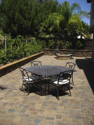 BACKYARD RENOVATION - This client's backyard was completely reimagined for a resort-like living space. A brick paver patio creates utilitarian space for dining and an integrated gas fire pit for lounging. Retaining walls create a raised garden area and their wide caps provide additional seating for entertaining. Lush plantings and an irrigation system were installed in the beds.