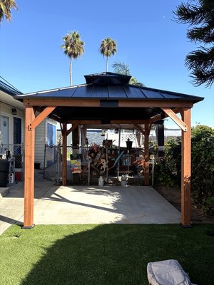 The Gazebo - Complete backyard gazebo assembly and installation, including the wood frame, structural supports, hardware, and metal hardtop roof. Carefully aligned and secured for a clean, durable finish and a comfortable outdoor living space. The Gazebo - Complete backyard gazebo assembly and installation, including the wood frame, structural supports, hardware, and metal hardtop roof. Carefully aligned and secured for a clean, durable finish and a comfortable outdoor living space.