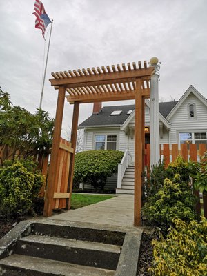 Cedar fence with a custom pergola-style entryway - This project features a beautifully crafted cedar fence with a custom pergola-style entryway, designed to enhance both privacy and curb appeal. The solid wood panels provide a warm, natural look that complements the home’s exterior, while the open-top pergola gate creates an inviting focal point for the entrance. Built with high-quality materials and precise craftsmanship, this fence not only defines the property boundary but also adds architectural charm and lasting durability. Cedar fence with a custom pergola-style entryway - This project features a beautifully crafted cedar fence with a custom pergola-style entryway, designed to enhance both privacy and curb appeal. The solid wood panels provide a warm, natural look that complements the home’s exterior, while the open-top pergola gate creates an inviting focal point for the entrance. Built with high-quality materials and precise craftsmanship, this fence not only defines the property boundary but also adds architectural charm and lasting durability.