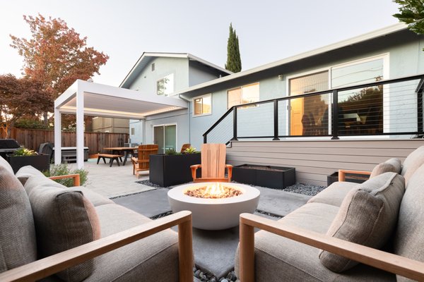 Sunnyvale Modern Courtyard & Backyard Renovation - When this family relocated from Chicago to Sunnyvale, they traded a larger home for an 1,800-square-foot residence in the heart of Silicon Valley. With both parents working from home, the outdoor space needed to function as a true extension of the house—supporting daily routines, moments of retreat, and active family life.

The challenge was clear: a compact yard, a two-level floor plan, and a long list of priorities.

They envisioned a garden that could accommodate multiple uses at once—comfortable lounging, hot tub access, dining and entertaining, lush planting, and dedicated space for vegetable gardening and rotating seasonal planters. All of this had to fit within a limited footprint, while remaining visually calm and connected to the home’s upper-level living spaces.

Our approach focused on organization, elevation, and clarity of use.

Rather than treating the yard as a single open area, the garden was divided into a series of outdoor “rooms,” each with a clear purpose. Large-format concrete pavers and gravel joints establish structure and rhythm, while allowing water to drain naturally and softening the overall composition. Built-in planters provide opportunities for edible gardens and changing plant palettes without consuming valuable floor space.

A lower lounge zone anchors the garden, centered around a fire feature and framed by layered planting for privacy and softness. Above, a dining and gathering area connects directly to the home, covered by a pergola that defines space while maintaining light and openness. The hot tub is integrated discreetly into the layout, accessible yet visually balanced within the broader design.

Throughout the garden, planting was used intentionally—not as filler, but as a functional element. Evergreen screening creates enclosure, while a mix of texture and seasonal interest brings the landscape to life without overwhelming the small footprint.

The result is a garden that feels larger than it is—one that supports work, rest, and play in equal measure. By carefully layering uses and responding to the home’s vertical layout, the outdoor space now offers the flexibility and richness of a much larger property, thoughtfully tailored to a modern family’s daily life.

Opulands is a family-owned Bay Area company specializing in comprehensive landscape and hardscape design and installation. We transform outdoor spaces into stunning retreats by blending softscaping elements like lawns and gardens with hardscaping features such as paver driveways, patios, and outdoor kitchens. Our team is dedicated to creating functional and opulent environments that enhance your lifestyle. Experience the beauty and functionality of a meticulously designed outdoor space. Call us today at 844-306-8953 for more information.