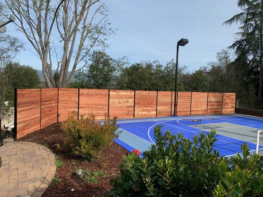 Horizontal Fence Tennis Court - This custom residence was designed to reflect the owner's vision, featuring horizontally oriented redwood cladding framed in metal. The combination of natural warmth and industrial precision resulted in a striking architectural finish that balances modern aesthetics with timeless materials."