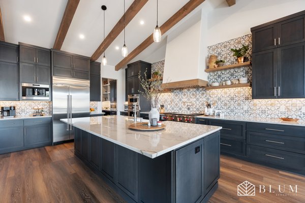 Santa Rosa Kitchen Remodel – Custom Cabinetry, Exposed Beams & Tile Accent - This full kitchen renovation in Santa Rosa brought a sophisticated mix of warmth and elegance to our client’s home. The original kitchen lacked character and functionality—so we completely reimagined the space from the ground up.
We installed custom, full-height shaker cabinets in a rich charcoal finish, complemented by dramatic exposed wood beams and a statement patterned tile backsplash. The oversized island features a polished stone countertop with ample prep space and seating, perfect for entertaining. Built-in appliances were seamlessly integrated into the cabinetry, including a built-in coffee machine, double ovens, and a premium Sub-Zero refrigerator.
Natural wood shelving, a farmhouse sink, and a large range hood with wood-wrapped trim add rustic charm without compromising on modern performance. Wide plank engineered hardwood flooring and strategically placed lighting complete the high-end, functional design.
Every element was chosen to balance timeless craftsmanship with everyday usability. The result is a space that feels both elevated and livable—designed for real life. Santa Rosa Kitchen Remodel – Custom Cabinetry, Exposed Beams & Tile Accent - This full kitchen renovation in Santa Rosa brought a sophisticated mix of warmth and elegance to our client’s home. The original kitchen lacked character and functionality—so we completely reimagined the space from the ground up.
We installed custom, full-height shaker cabinets in a rich charcoal finish, complemented by dramatic exposed wood beams and a statement patterned tile backsplash. The oversized island features a polished stone countertop with ample prep space and seating, perfect for entertaining. Built-in appliances were seamlessly integrated into the cabinetry, including a built-in coffee machine, double ovens, and a premium Sub-Zero refrigerator.
Natural wood shelving, a farmhouse sink, and a large range hood with wood-wrapped trim add rustic charm without compromising on modern performance. Wide plank engineered hardwood flooring and strategically placed lighting complete the high-end, functional design.
Every element was chosen to balance timeless craftsmanship with everyday usability. The result is a space that feels both elevated and livable—designed for real life.