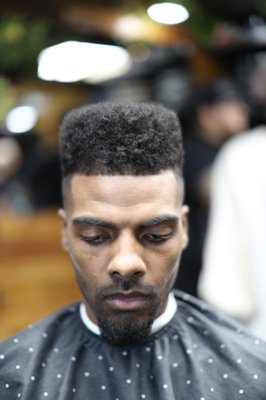 Low Fade Afro - A low fade afro paired with a clean sharp line-up. The cut emphasizes natural curl definition on top while maintaining smooth transitions on the sides for a balanced, structured finish. Detailed edging completes the look for a crisp, professional result. Low Fade Afro - A low fade afro paired with a clean sharp line-up. The cut emphasizes natural curl definition on top while maintaining smooth transitions on the sides for a balanced, structured finish. Detailed edging completes the look for a crisp, professional result.