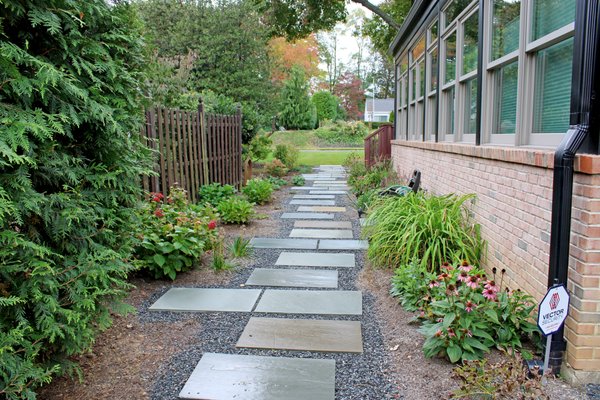 Backyard Renovation - This narrow back yard was consistently wet and as a result the grass never really had a chance. 

We put a French drain in the middle of the walkway under the bluestone then installed a infiltration trench that took the downspout water from the back side of the house and placed it under ground.  The infiltration trench has a total of 60' of 12" perforated pipe surrounded by stone with a overflow in a rear garden bed. This area was then backfilled with soil and sodded. The water enters the system then seeps back into the ground with minimal runoff.

With a new walkway and gardens installed the backyard is a beautiful place that the family can now enjoy, even right after a rainfall.