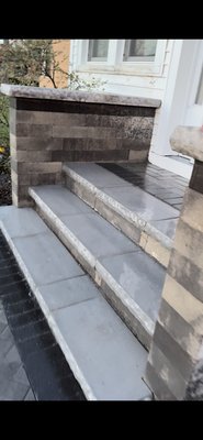 Custom Front Paver Steps & Walkway Connecting to Driveway - Complete front entrance upgrade featuring custom-built paver steps and a professionally installed paver sidewalk leading directly to the driveway. This project included full excavation, solid base preparation, and precision installation in a clean herringbone pattern with contrasting border accents. The steps were constructed using durable wall block and finished with smooth stone caps for a modern, elegant appearance. This installation enhances curb appeal, improves accessibility, and creates a welcoming, high-end entrance to the home.