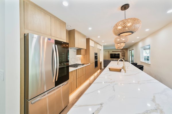 Kitchen Remodel - ✨ Modern Kitchen Transformation – From Dated to Designer Elegance
This full kitchen renovation showcases how strategic design choices and superior craftsmanship can reimagine a home’s most important space.
🔨 Before
The original kitchen was enclosed and outdated, with bulky upper cabinets, worn wood finishes, and poor lighting. It felt disconnected from the rest of the home and lacked both storage efficiency and visual appeal.
🛠️ The Transformation
We completely restructured the layout, enhancing the openness and sightlines throughout the kitchen and adjacent living area. One of the standout upgrades in this remodel is the installation of premium European frameless cabinetry, which brings both modern style and functional excellence.
🌍 Why European Frameless Cabinets?
Unlike traditional framed cabinets, European frameless cabinetry offers a sleek, seamless appearance and full access to interior storage. The clean lines and minimalist profile deliver a contemporary aesthetic while maximizing usable space. Key benefits include:
Full-overlay slab doors for a continuous, streamlined look
Precision soft-close hardware for a smooth, high-end feel
Optimized storage capacity with no face frame obstructions
Superior craftsmanship using durable, moisture-resistant materials
These cabinets were custom-fit to the space and finished in a warm, light-toned wood that blends beautifully with the veined quartz countertops and brass fixtures.
✨ After
The new kitchen is both a showpiece and a practical workhorse. The dramatic island, statement lighting, and subtle textures elevate the space without overwhelming it. Paired with top-of-the-line appliances and thoughtful layout planning, this remodel delivers a perfect fusion of European design sensibility and everyday functionality. Kitchen Remodel - ✨ Modern Kitchen Transformation – From Dated to Designer Elegance
This full kitchen renovation showcases how strategic design choices and superior craftsmanship can reimagine a home’s most important space.
🔨 Before
The original kitchen was enclosed and outdated, with bulky upper cabinets, worn wood finishes, and poor lighting. It felt disconnected from the rest of the home and lacked both storage efficiency and visual appeal.
🛠️ The Transformation
We completely restructured the layout, enhancing the openness and sightlines throughout the kitchen and adjacent living area. One of the standout upgrades in this remodel is the installation of premium European frameless cabinetry, which brings both modern style and functional excellence.
🌍 Why European Frameless Cabinets?
Unlike traditional framed cabinets, European frameless cabinetry offers a sleek, seamless appearance and full access to interior storage. The clean lines and minimalist profile deliver a contemporary aesthetic while maximizing usable space. Key benefits include:
Full-overlay slab doors for a continuous, streamlined look
Precision soft-close hardware for a smooth, high-end feel
Optimized storage capacity with no face frame obstructions
Superior craftsmanship using durable, moisture-resistant materials
These cabinets were custom-fit to the space and finished in a warm, light-toned wood that blends beautifully with the veined quartz countertops and brass fixtures.
✨ After
The new kitchen is both a showpiece and a practical workhorse. The dramatic island, statement lighting, and subtle textures elevate the space without overwhelming it. Paired with top-of-the-line appliances and thoughtful layout planning, this remodel delivers a perfect fusion of European design sensibility and everyday functionality.
