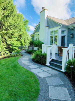 Glenview Retreat - This landscape renovation took place over several years and multiple phases. The original landscape was overrun by a thicket of buckthorn that encroached on the house. The first step was to remove the buckthorn and reclaim the west side yard, improve the drainage, and install a heated clay paver drive. The extensive border plantings are loaded with colorful perennials, hydrangea, and hibiscus that add color and texture from early spring throughout late fall. Bluestone walkways lead guests from the drive or street to the front entry flanked by seasonal containers. Once an open lawn, the back yard was converted into a private retreat for the family and now includes a pool, hot tub, pergola, fireplace, outdoor kitchen, garden shed, landscape lighting, and lush plantings. Site limitations paired with an intensive permit process posed several obstacles, but the design solution met the challenge. In lieu of a paved patio, an at-grade deck serves as the central element tying together all entertainment spaces and providing appropriate site drainage. The fireplace and pergola were constructed to complement the architecture of the home, while the backyard planting scheme is packed with colorful plants to seamlessly tie into the border plantings installed years earlier. Glenview Retreat - This landscape renovation took place over several years and multiple phases. The original landscape was overrun by a thicket of buckthorn that encroached on the house. The first step was to remove the buckthorn and reclaim the west side yard, improve the drainage, and install a heated clay paver drive. The extensive border plantings are loaded with colorful perennials, hydrangea, and hibiscus that add color and texture from early spring throughout late fall. Bluestone walkways lead guests from the drive or street to the front entry flanked by seasonal containers. Once an open lawn, the back yard was converted into a private retreat for the family and now includes a pool, hot tub, pergola, fireplace, outdoor kitchen, garden shed, landscape lighting, and lush plantings. Site limitations paired with an intensive permit process posed several obstacles, but the design solution met the challenge. In lieu of a paved patio, an at-grade deck serves as the central element tying together all entertainment spaces and providing appropriate site drainage. The fireplace and pergola were constructed to complement the architecture of the home, while the backyard planting scheme is packed with colorful plants to seamlessly tie into the border plantings installed years earlier.