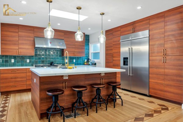Kitchen Remodel 2025 - This stunning kitchen remodel blends modern elegance with timeless craftsmanship, creating a warm and functional space perfect for everyday living and entertaining. The design features rich wood cabinetry paired with a bold green tile backsplash, offering a refined balance of color and texture. A spacious island with a sleek waterfall countertop serves as both a visual centerpiece and a practical gathering spot, complemented by custom pendant lighting that enhances the room’s ambiance. Premium stainless-steel appliances and gold-accented fixtures add a touch of sophistication, while the detailed wood flooring ties the entire space together with character and charm. Every element—from layout to finish—was thoughtfully executed to ensure lasting beauty, comfort, and functionality, showcasing Edri Construction’s commitment to quality and design excellence. Kitchen Remodel 2025 - This stunning kitchen remodel blends modern elegance with timeless craftsmanship, creating a warm and functional space perfect for everyday living and entertaining. The design features rich wood cabinetry paired with a bold green tile backsplash, offering a refined balance of color and texture. A spacious island with a sleek waterfall countertop serves as both a visual centerpiece and a practical gathering spot, complemented by custom pendant lighting that enhances the room’s ambiance. Premium stainless-steel appliances and gold-accented fixtures add a touch of sophistication, while the detailed wood flooring ties the entire space together with character and charm. Every element—from layout to finish—was thoughtfully executed to ensure lasting beauty, comfort, and functionality, showcasing Edri Construction’s commitment to quality and design excellence.