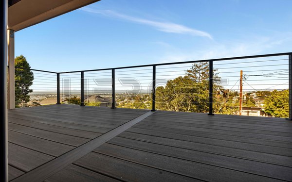 Modern Deck & Railing Installation | Wooster Ave, Belmont, CA - A complete exterior upgrade for this multi-level Belmont home, designed to maximize outdoor living space and capture the panoramic views. This project features premium dark composite decking paired with sleek, modern black cable railings on both the upper and lower decks. The minimal design ensures completely unobstructed views from every angle. The renovation also includes a beautifully integrated hillside wooden staircase and a matching pergola system that connects the landscaped garden to the home's updated modern exterior.