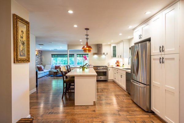 Kitchen & Living Room Remodel in Santa Monica - We enhance the storage space of this kitchen by creating new kitchen cabinets and installing a kitchen island with drawers. We replaced the countertops with a beautiful smooth white marble countertop. Paired with a classic white subway tile backsplash, this kitchen naturally beams of light.