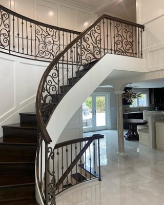 Grand Foyer - We worked with our client to design the custom grand foyer railings of her dreams. With hand forged scrolls, alternating collars, and a wood cap, this curved project certainly makes a statement when you walk in the door!