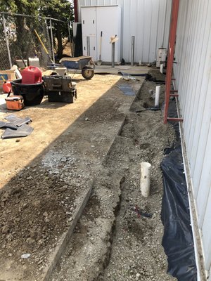 Solano Commercial Building with Water Intrusion - Drainage Project in Solano County-This Project Owner had water intrusion into his building from the left side of his building. The neighboring property sat 4' above his and during the rains water collected next to his building and come in over the slab. Drainage Pros designed a French drainage system along with a surface drainage system including catch basins to collect surface water and the French drainage system collect the ground water moving it over to a sump pit location. The sump pump in the sump pit discharged the unwanted water out thru the front curb. This Project was completed in 2020 and made it thru the 2022 rains without a problem. The building Owner now has dry floors and his tenants are very happy! Solano Commercial Building with Water Intrusion - Drainage Project in Solano County-This Project Owner had water intrusion into his building from the left side of his building. The neighboring property sat 4' above his and during the rains water collected next to his building and come in over the slab. Drainage Pros designed a French drainage system along with a surface drainage system including catch basins to collect surface water and the French drainage system collect the ground water moving it over to a sump pit location. The sump pump in the sump pit discharged the unwanted water out thru the front curb. This Project was completed in 2020 and made it thru the 2022 rains without a problem. The building Owner now has dry floors and his tenants are very happy!