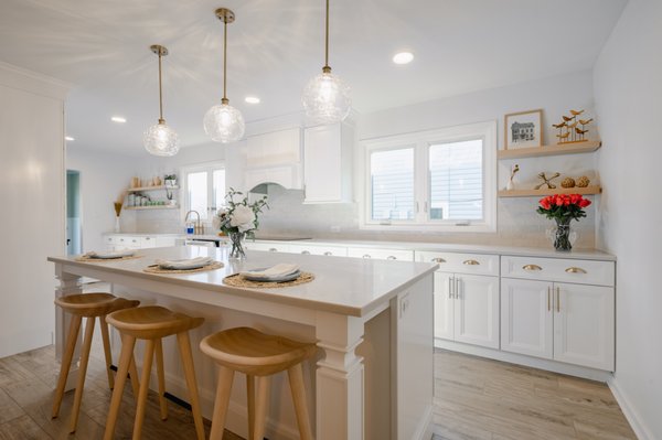 Modern White Kitchen Remodel in Hoffman Estates - A full kitchen overhaul in Hoffman Estates, IL featuring white cabinetry, custom quartz countertops, brushed gold hardware accents, glossy white ceramic tile backsplash, and light wood-look vinyl plank flooring.