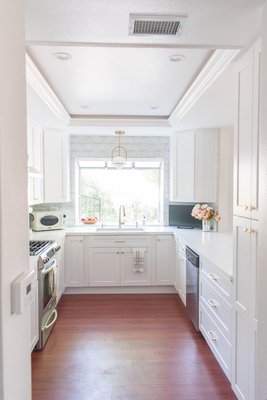 Kitchen Remodel - Westlake Village - Although on the smaller side, this kitchen needed an uplift, and that is exactly what it got. The custom apartment kitchen remodel turned into a beautiful modern design with accents of white and textured tiles that truly harmonized the space while helping reflect the natural light in the room. In addition wood flooring on the entire first floor of the apartment was installed to allow for an overall clean look and contrast to the white kitchen and light walls of the space. Kitchen Remodel - Westlake Village - Although on the smaller side, this kitchen needed an uplift, and that is exactly what it got. The custom apartment kitchen remodel turned into a beautiful modern design with accents of white and textured tiles that truly harmonized the space while helping reflect the natural light in the room. In addition wood flooring on the entire first floor of the apartment was installed to allow for an overall clean look and contrast to the white kitchen and light walls of the space.