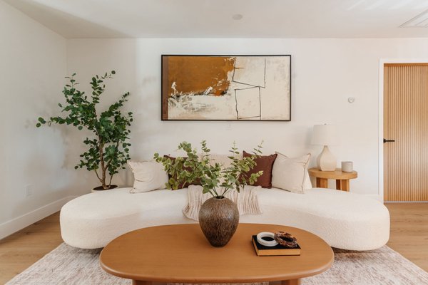 576 Neva Pl Los Angeles, CA - This project shows a beautifully staged open-concept living and dining area with a warm, modern aesthetic. A curved white sofa with textured pillows sits on a soft neutral rug, accented by a wooden coffee table and greenery for a natural touch. Large abstract artwork adds sophistication on the walls, while the adjacent dining space features a sleek wood table with matching chairs and a statement pendant light. The overall look is inviting, airy, and perfectly designed to help buyers imagine themselves living in the home. 576 Neva Pl Los Angeles, CA - This project shows a beautifully staged open-concept living and dining area with a warm, modern aesthetic. A curved white sofa with textured pillows sits on a soft neutral rug, accented by a wooden coffee table and greenery for a natural touch. Large abstract artwork adds sophistication on the walls, while the adjacent dining space features a sleek wood table with matching chairs and a statement pendant light. The overall look is inviting, airy, and perfectly designed to help buyers imagine themselves living in the home.
