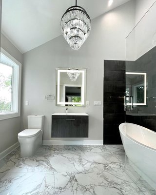 Short Hills Master Bathroom Remodel: From Dated to Dazzling! - Check out this incredible before and after! We completely reimagined this space in Short Hills, NJ, replacing the outdated tile and red walls with a chic, high-end design. The new master bathroom features striking large-format marble-look floor tiles, a dramatic free-standing soaking tub backed by modern dark tile, and a luxurious rain shower. The sleek floating vanity, backlit mirror, and crystal chandelier complete this glamorous, spa-like retreat. Short Hills Master Bathroom Remodel: From Dated to Dazzling! - Check out this incredible before and after! We completely reimagined this space in Short Hills, NJ, replacing the outdated tile and red walls with a chic, high-end design. The new master bathroom features striking large-format marble-look floor tiles, a dramatic free-standing soaking tub backed by modern dark tile, and a luxurious rain shower. The sleek floating vanity, backlit mirror, and crystal chandelier complete this glamorous, spa-like retreat.