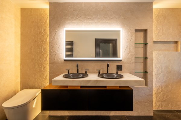 Bathroom Remodel Hollywood Hills - ✨ Bathroom Remodel Reveal ✨
We transformed this bathroom into a sleek, modern retreat blending warmth and luxury:
Custom Floating Vanity – Matte black cabinetry with natural wood accents topped with a solid marble slab. Double vessel sinks in textured black stone pair perfectly with matte black fixtures for a bold, contemporary look.
Statement Lighting – An oversized LED backlit mirror adds both function and ambiance, making the space feel bright and spacious.
Spa-Like Features – A freestanding soaking tub set against large windows brings in natural light and creates a calming, resort-inspired feel.
Walk-In Shower – Frameless glass with full-height stone-look tile and matte black hardware gives a clean, minimalistic finish.
Designer Details – Textured wall tile, integrated shelving, and hidden storage add depth and functionality without clutter.
The result: a balance of modern sophistication and natural comfort – the perfect space to unwind at the end of the day. 🌿🛁