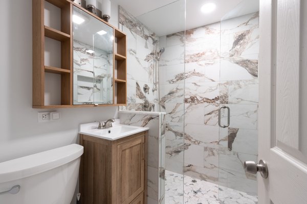 Bathroom Remodel in Palatine - This small Palatine bathroom needed more than a refresh, it needed a full reset. We wrapped the walk-in shower in a bold, dramatic tile pattern that runs floor to ceiling, added a wood vanity with a white quartz counter for a clean, open feel, and swapped the old shower door for frameless glass so the tile could really shine. The result is a bathroom that feels twice its size. Bathroom Remodel in Palatine - This small Palatine bathroom needed more than a refresh, it needed a full reset. We wrapped the walk-in shower in a bold, dramatic tile pattern that runs floor to ceiling, added a wood vanity with a white quartz counter for a clean, open feel, and swapped the old shower door for frameless glass so the tile could really shine. The result is a bathroom that feels twice its size.