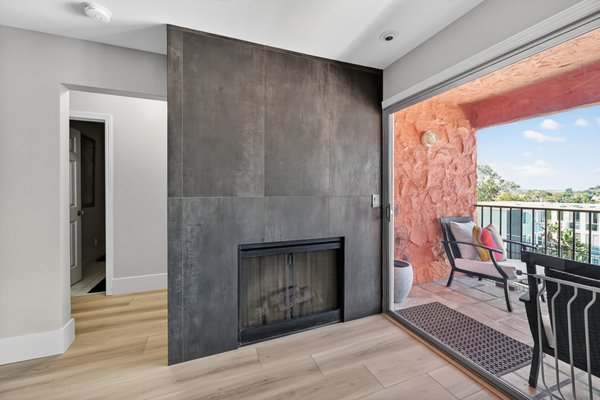 Powder Room & Fireplace Remodel - Hillcrest - A sleek, modern powder room featuring clean white cabinetry, a marble countertop, and a softly backlit mirror that adds a touch of elegance to the minimalist design. Also a modern living space with fireplace and large sliding doors opening to a cozy balcony, blending indoor comfort with bright outdoor views.