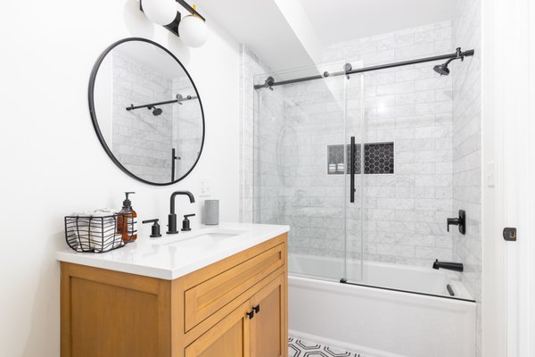 Bathroom Remodel - Oceanside - This bright, space-efficient bathroom renovation combines natural warmth with crisp modern contrast. By pairing a warm wood vanity with high-contrast matte black hardware, clean white quartz, and classic marble-look surround tile, the redesign delivers a stylish and functional guest or family bath. Bathroom Remodel - Oceanside - This bright, space-efficient bathroom renovation combines natural warmth with crisp modern contrast. By pairing a warm wood vanity with high-contrast matte black hardware, clean white quartz, and classic marble-look surround tile, the redesign delivers a stylish and functional guest or family bath.