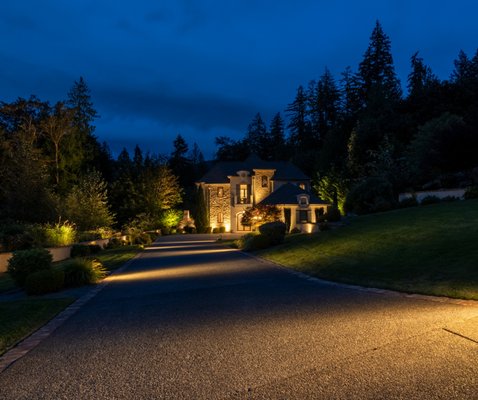 Issaquah Residence - The lighting design for this Issaquah manor emphasizes elegance and functionality, creating an inviting atmosphere that enhances the home's architectural beauty and the natural surroundings. The design strategically employs warm-toned LED lights to illuminate the home's exterior, driveway, and landscaping, ensuring both safety and aesthetics. The lighting scheme is tailored to accentuate the stone façade of the manor and the lush greenery, providing a soft contrast that highlights textures and colors without overpowering the natural nighttime ambience. Issaquah Residence - The lighting design for this Issaquah manor emphasizes elegance and functionality, creating an inviting atmosphere that enhances the home's architectural beauty and the natural surroundings. The design strategically employs warm-toned LED lights to illuminate the home's exterior, driveway, and landscaping, ensuring both safety and aesthetics. The lighting scheme is tailored to accentuate the stone façade of the manor and the lush greenery, providing a soft contrast that highlights textures and colors without overpowering the natural nighttime ambience.