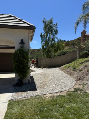 Pebble/ Walkway installation - The job entailed preparing a designated area before laying down the pebbles and creating a walkway. The preparation included removing approximately 4 inches of impervious soil, forming the walkway, capping existing irrigation lines, etc. 

The material used in the photo is Bulk Del Rio Pebbles (1 inch) and 16" x 16" Belle Cobble Step Stones.