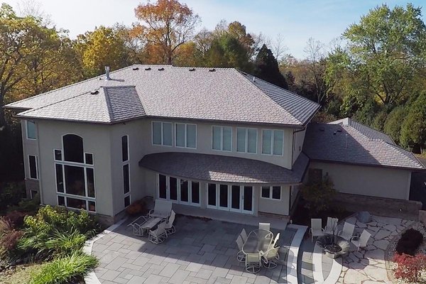 Mequon, WI - Lakeshore Roof & Gutters - This lakeshore home was originally built in 1994. The roof was covered with DaVinci multi-width composite slate. BCI worked for months with both the homeowners and DaVinci designers to come up with a perfect custom color for this roof. DaVinci Slate is a complete line of synthetic slate roofing materials that are natural in appearance, incredibly durable, and easy to install.

One of the unique features of the home was the section of roof above the back patio. Traditionally, a section of roof like this would feature horizontal lines and an angular peak, but here, the line where the roof met the side of the house barreled vertically and had a rounded edge, similar to a turret. This made it a fun challenge, to meticulously cut and apply the slate tiles and wrap the rounded edge of the roof with gutters, but the end result speaks for itself.

The overall square footage of the roof and the amount of water it drained during rainfall factored into the size of gutter needed for the house. Six-inch copper K-style gutters were chosen instead of the traditional five-inch K-style. Copper is by far one of the most durable materials out there for such a system and also adds to the design and aesthetic of the home.